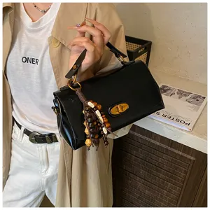 Close-up of a stylish black retro small square handbag featuring a beaded tassel charm