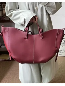 Large burgundy pebbled leather tote with white contrast stitching and unique curved silhouette.