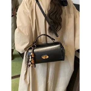 Vintage black rectangular handbag with elegant gold twist lock and beaded charm detail.