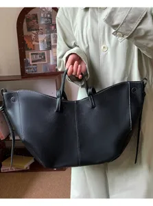 Detailed view of a large black pebbled leather tote bag with contrast white stitching
