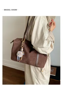 Detail shot of a large brown suede bowling bag carried by a model in a beige trench coat
