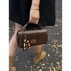 Retro brown leather handbag detail shot with a stylish beaded tassel charm pendant