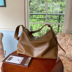 Large minimalist brown soft leather hobo bag for commuting in a cozy lifestyle home setting