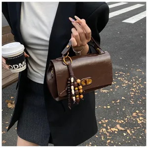 Street style view of a retro dark brown leather handbag featuring wooden bead tassel charm