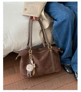 Close-up of vintage brown suede bowling bag with cute furry charm and gold zippers.