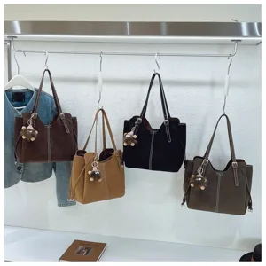 Display of four large capacity tote bags in earthy tones with furry monster keychains.