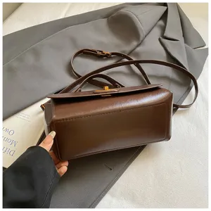 Close-up of vintage dark brown square bag showing leather texture and gold clasp