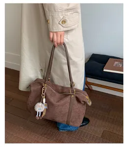 Detail showing the retro brown suede bowling bag held by a person in a trench coat