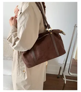 Macro detail of a vintage brown suede bowling bag worn by a model in a beige coat.