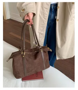 Detail view of a vintage brown suede bowling bag held by a model in a trench coat.