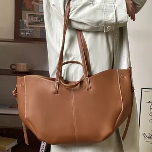 Minimalist large brown leather tote bag in bucket shape with contrast white stitching