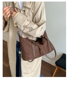Large capacity retro brown suede bowling bag carried by a model in a trench coat.