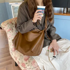 Minimalist slouchy brown leather hobo bag for women presented in a lifestyle cafe setting