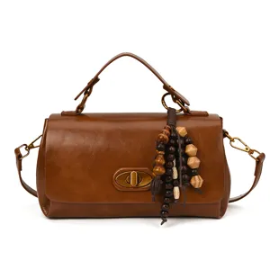Elegant vintage brown leather handbag featuring a retro bead tassel and top handle strap