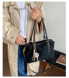 Model carrying a vintage black suede Boston bag with gold hardware and pom-pom charm