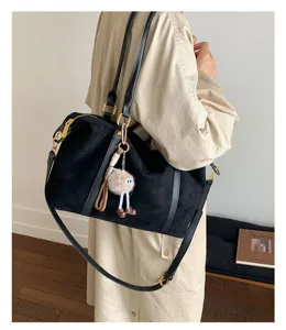 Black suede Boston bag styled with a beige trench coat in a minimalist indoor setting