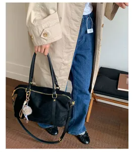 Model carrying a large black suede Boston bag in a stylish and elegant lifestyle setting.