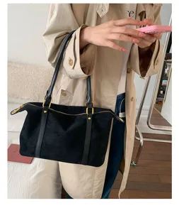 Large black vintage bowling bag with gold hardware held by a model in a beige trench coat