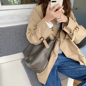 Large minimalist slouchy shoulder bag in soft leather worn with khaki trench coat