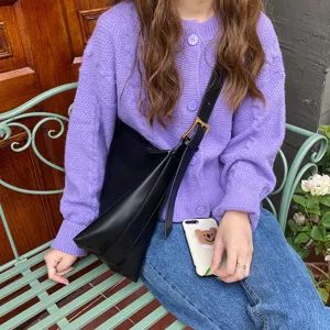Minimalist black soft leather shoulder bag for women in a casual outdoor lifestyle setting