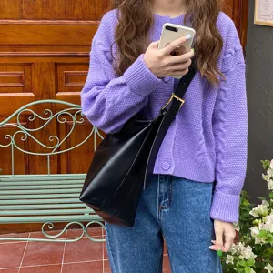 Model wearing a minimalist black soft leather shoulder bag for chic daily commuting