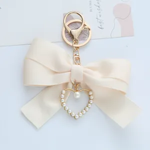 Close-up detail of the elegant cream ribbon bow and pearl-encrusted heart charm