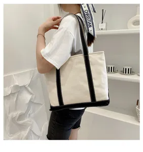 Side view of a large canvas tote bag with black straps carried by a woman