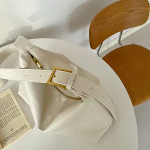 Close-up of a minimalist soft leather shoulder bag with a gold buckle detail