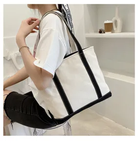 Detailed close-up showing a stylish white canvas tote bag with black trim carried by a fashion model.