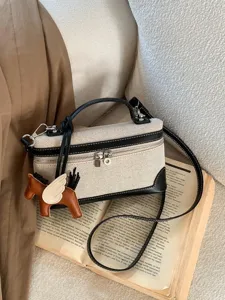 Stylish canvas crossbody square bag with black leather trim and a decorative horse charm.