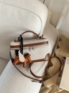 Elegant beige canvas crossbody handbag featuring brown leather trim and flying horse charm