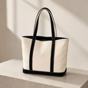 Detailed view of a minimalist canvas tote bag featuring black contrast trim on stone