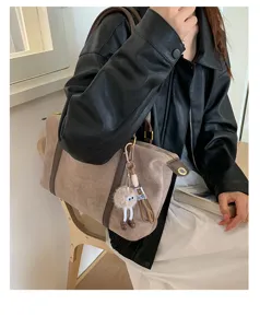 Detail view of a vintage taupe suede Boston bag carried by a model in a leather jacket