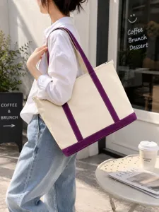 Detail of large beige canvas tote bag with purple straps carried by a model.
