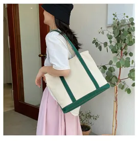 Stylish large capacity canvas tote bag with green accents shown on model in a lifestyle setting
