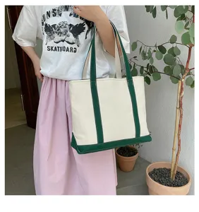 Woman carrying a large capacity white and green canvas tote bag in a casual outdoor setting