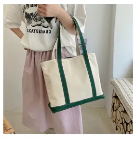 Detail shot of a women's cream canvas tote bag with green accents, styled with casual outfit.