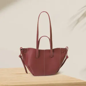Vintage burgundy leather wing tote bag with contrast stitching on wooden surface