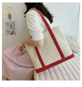 Large capacity canvas tote bag with vibrant red trim shown in a cozy interior setting