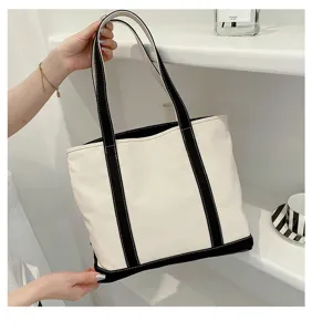 Detailed macro view of the minimalist cream canvas tote bag with black contrast straps