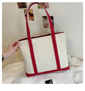 Close-up view of a large capacity canvas tote bag with red contrast handles and trim