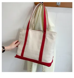 Detail view of a large capacity canvas tote bag with red straps hanging on a wall hook.