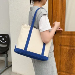 Casual large capacity canvas tote bag with blue trim carried by a woman in the street