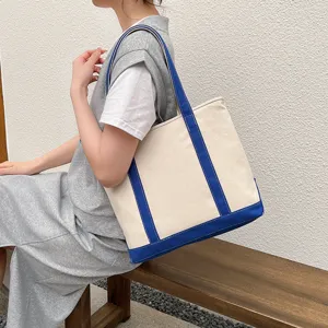 Casual off-white canvas tote bag with contrast blue straps shown in a lifestyle setting