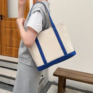 Detailed view of a large canvas tote bag with blue trim in a lifestyle setting.