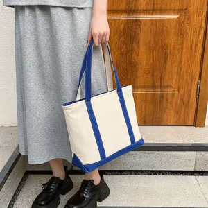 Close-up of a stylish cream and blue canvas tote bag showing handle detail and texture