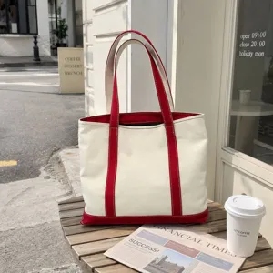 Large capacity cream canvas tote bag with red handles on a street cafe table setting