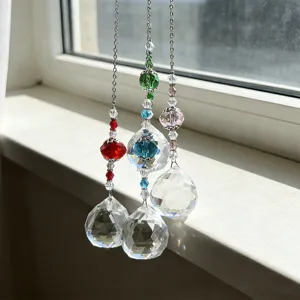 Macro detail of three faceted crystal sun catchers hanging by a bright window sill
