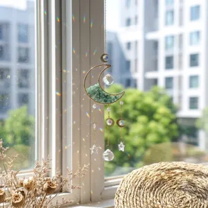 Nahaufnahme des Mond-Kristall-Sonnenfängers mit grünem Kies am hellen Fenster