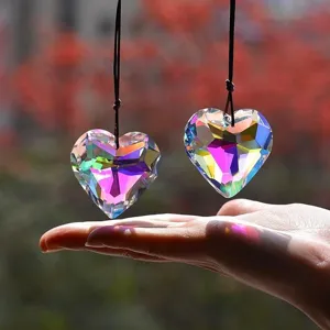 Primo piano di prismi acchiappasole in cristallo a cuore con rifrazione della luce arcobaleno.